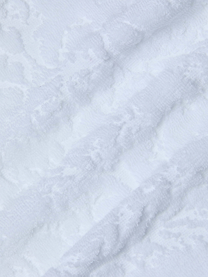 Close-up of the Caterina Cover-Up Robe's white cotton jacquard fabric, showcasing a subtle floral pattern with soft, raised textures and gentle diagonal lines for a wavy look.