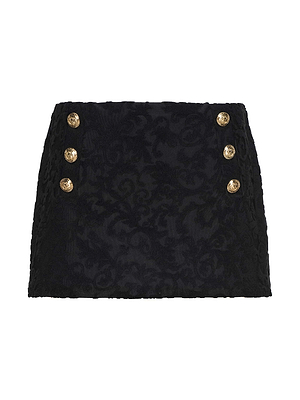 The Coco Swim Skirt is a black jacquard terry mini skirt with a subtle floral pattern and two rows of three gold decorative buttons on the front.