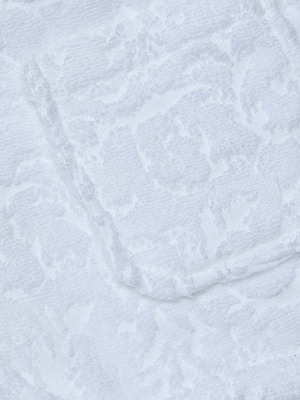 Close-up of textured white fabric with a subtle raised pattern, giving the Amiya Cover-Up Short a soft, elegant look—perfect as lightweight terrycloth resortwear.