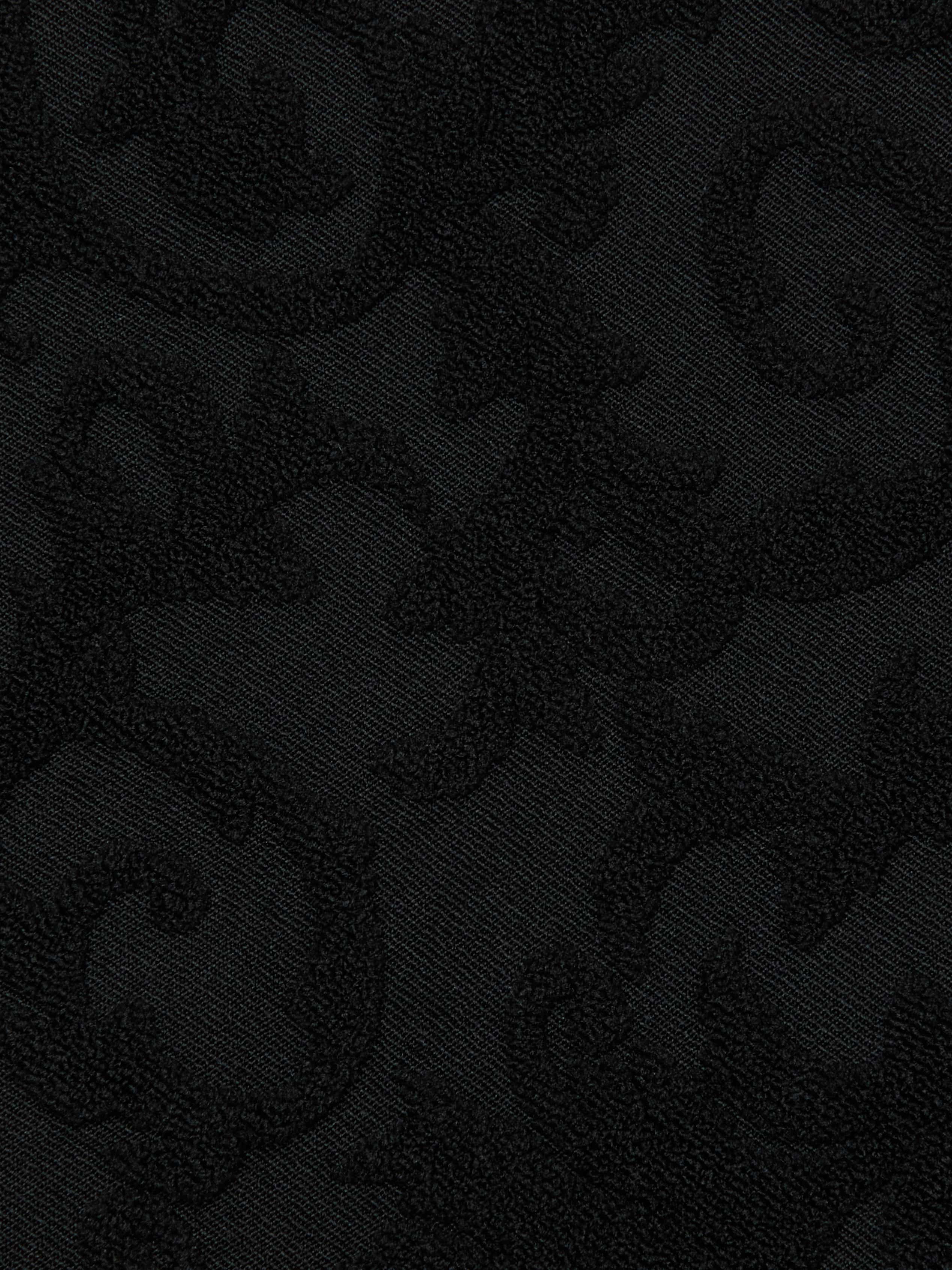 The Sally Bandeau Top features black jacquard terry fabric with a subtle, raised swirling floral pattern. Its textured design produces a tone-on-tone effect, giving the top an elegant and richly detailed look while maintaining a monochromatic black color scheme infused with retro glamour.