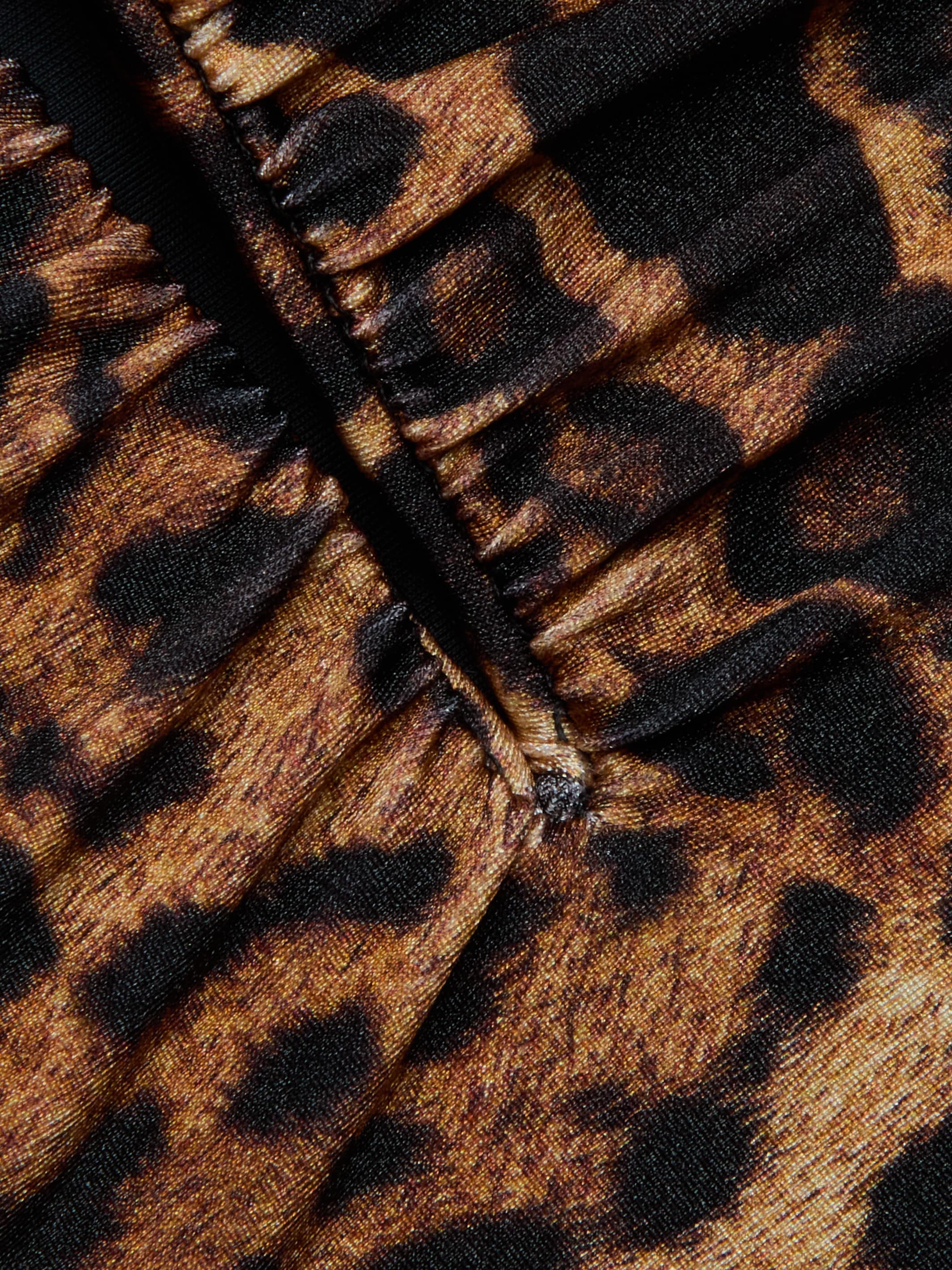 Close-up of gathered fabric from the Lilou One-Piece Swimsuit, showcasing its leopard print with brown and black spots and visible stitching down the center.