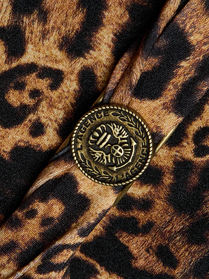 Close-up of a brass L'AGENCE button with leaf detail, sewn onto brown and black leopard print fabric on the Lisa Plunge One-Piece Swimsuit.