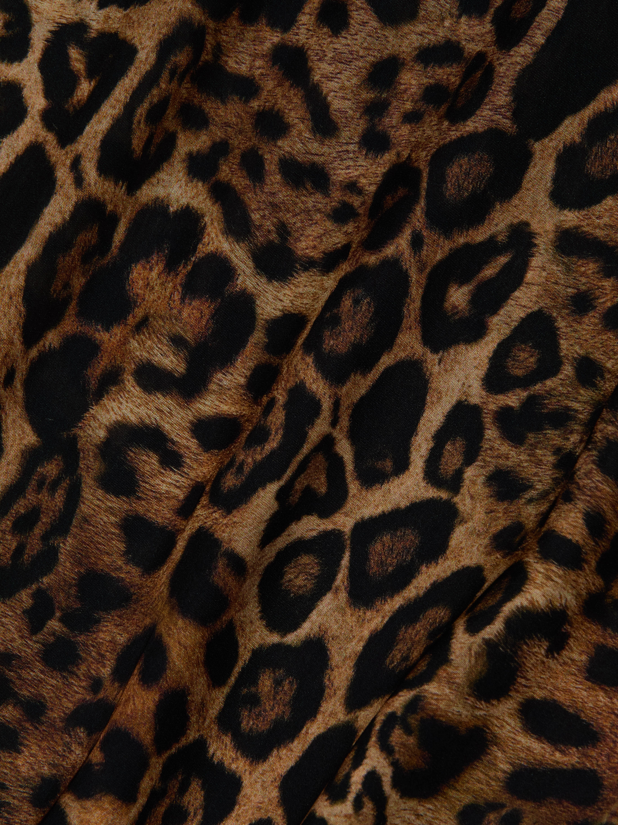 Close-up of the Geraldine Cover-Up Pant, showcasing leopard print fabric with black and dark brown spots on a tan background, visible folds, and a soft texture—ideal for resort wear or as wide leg pull-on pants.