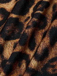 Close-up of fabric with a leopard print pattern, featuring black and brown spots on a tan background. The material, used for the Sirena Halter Bikini Top, displays visible folds and texture—perfect for bold swimwear style.