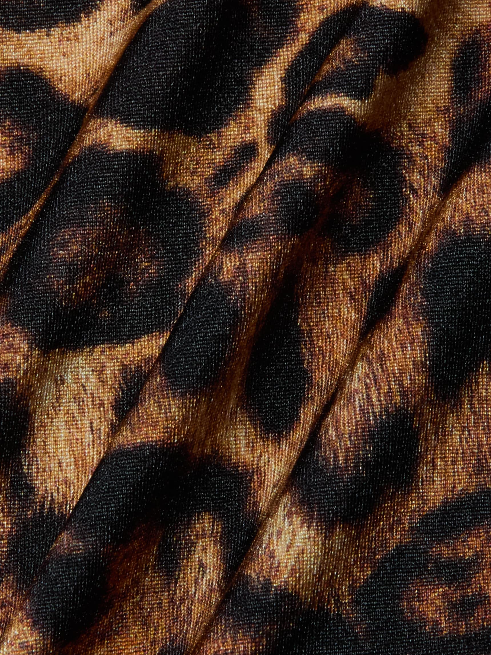 Close-up of fabric with a leopard print pattern, featuring black and brown spots on a tan background. The material, used for the Sirena Halter Bikini Top, displays visible folds and texture—perfect for bold swimwear style.