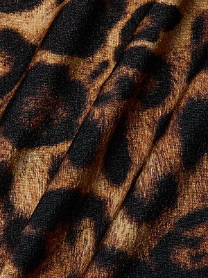Close-up of the Sirena Halter Bikini Top by L'AGENCE, showcasing leopard print fabric with irregular black and brown spots on a tan background. Slightly textured material and visible folds add dimension to this sexy swimwear piece.