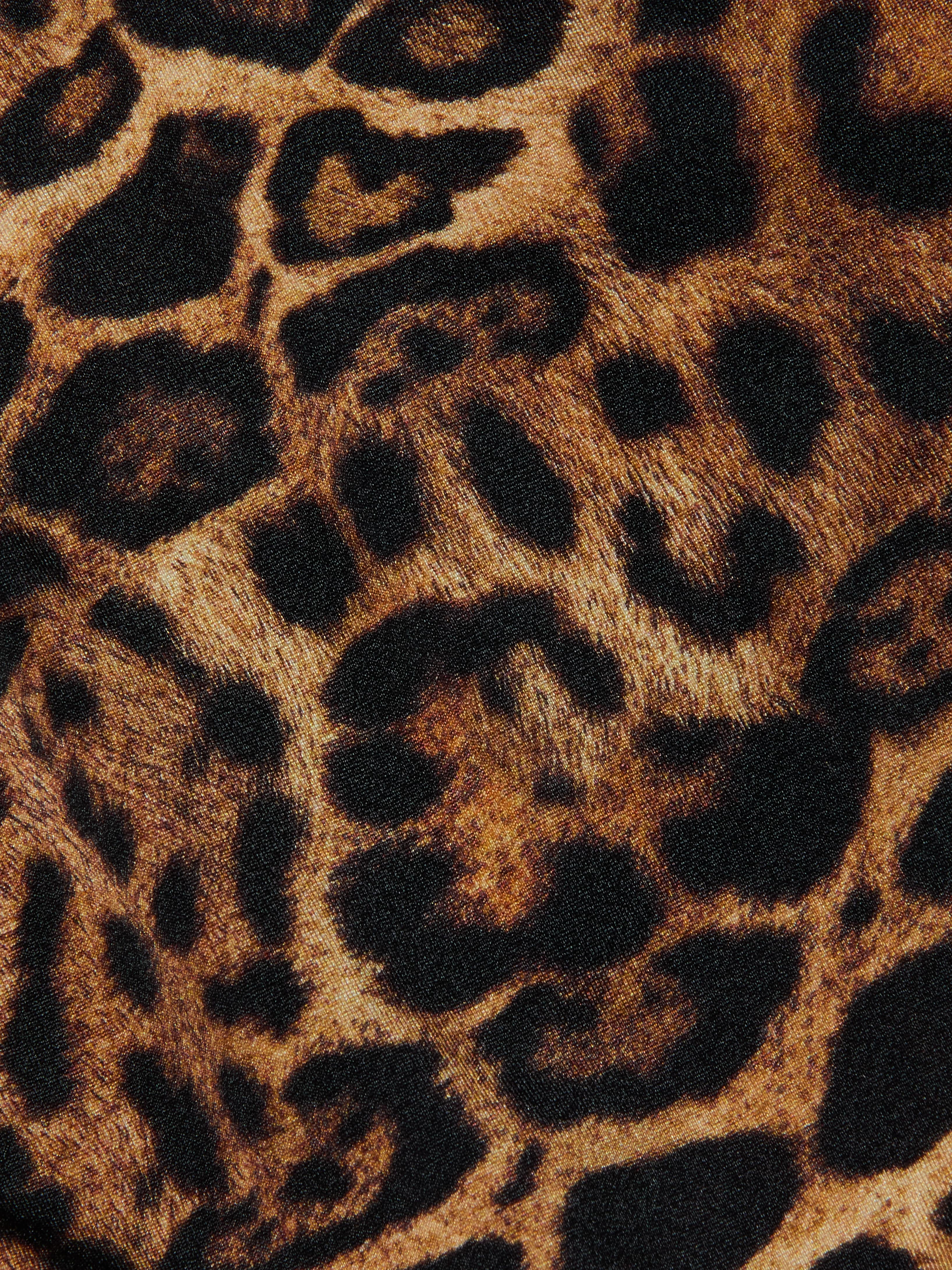 Close-up of the Britt Tie-Side Bikini Bottom fabric featuring a leopard print with black and brown spots on a tan background, mimicking wild animal fur—ideal for resort swimwear or adjustable tie-side styles.
