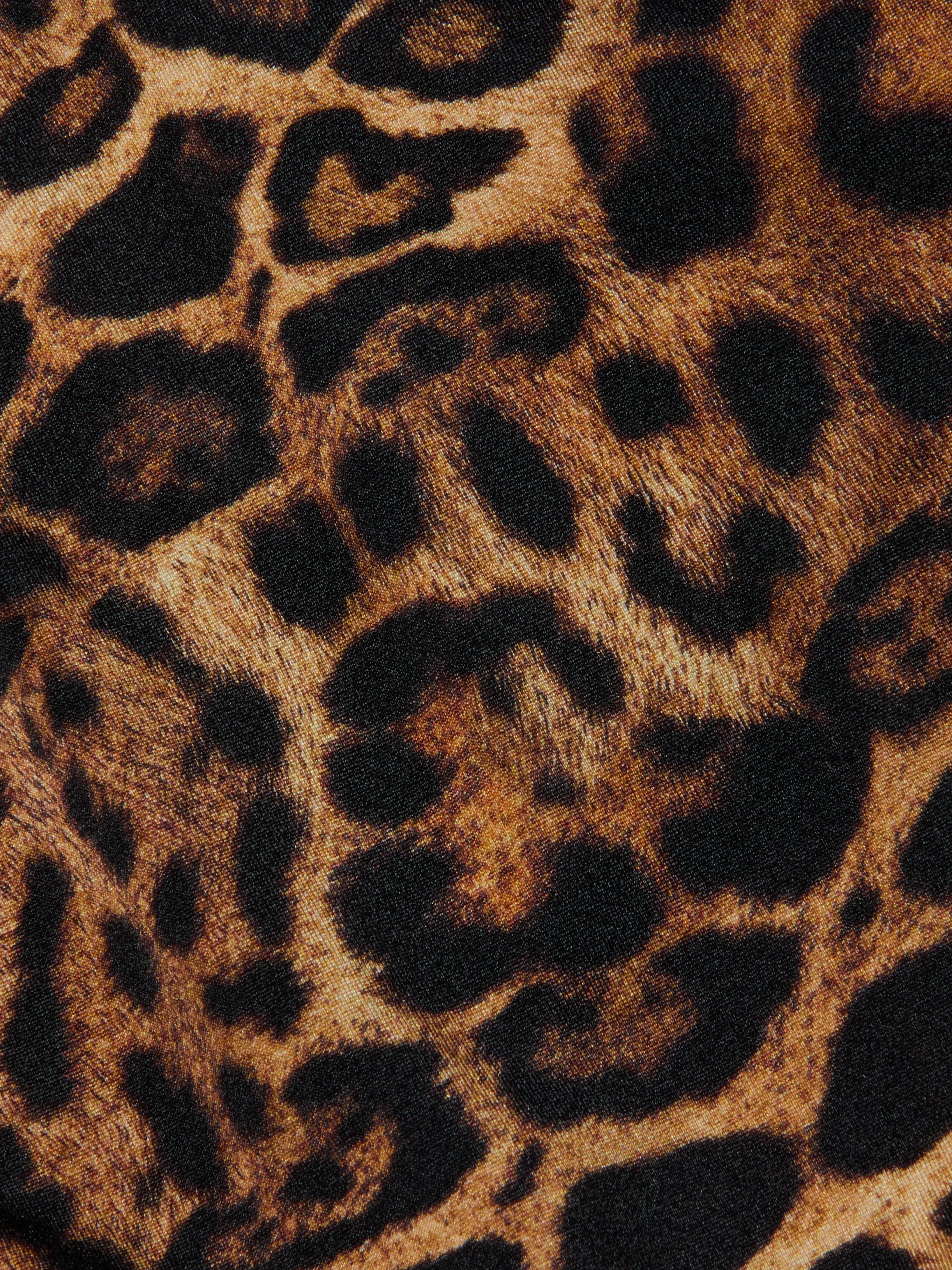 Close-up of the Britt Tie-Side Bikini Bottom fabric featuring a leopard print with black and brown spots on a tan background, mimicking wild animal fur—ideal for resort swimwear or adjustable tie-side styles.