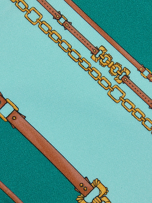 The L'AGENCE Tory Bandeau One-Piece Swimsuit features a chic belt-stripe print with brown leather belts and gold chains on a teal and light blue background—ideal for a stylish look.