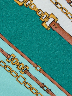 Close-up of fabric with gold chains and brown leather belts on green, turquoise, and white evokes luxury—perfect for the Lexie Bikini Top, featuring a sage belt-stripe pattern, gold deco hardware, and adjustable straps.