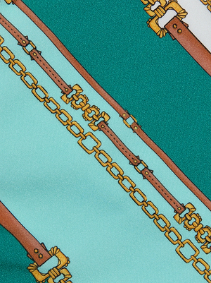 The Nicole Bikini Bottom features a patterned fabric in teal, light blue, and sage with printed gold chains and brown leather belts. Made from four-way stretch nylon, it offers enhanced comfort and flexibility.