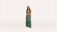 Woman wearing a green floral bikini top and matching long skirt standing barefoot against a plain white background.