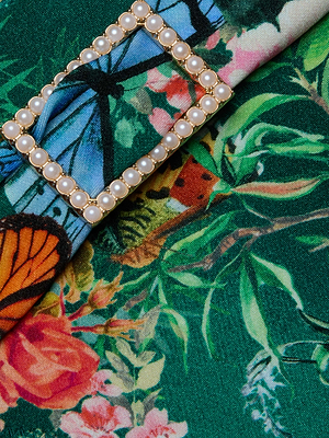 The Miya Bikini Bottom by L'AGENCE features moderate coverage, a pearl-studded rectangular buckle on the sash waistband, and an elegant botanical and butterfly print.