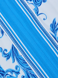The Kara Kimono Cover-Up features blue and white diagonal stripes accented with ornate blue floral and vine patterns. Crafted from water-safe viscose crepe, its decorative trim borders the flowing design, set against a mostly white background highlighted by intricate blue details—making it a perfect blue baroque-inspired cover-up.