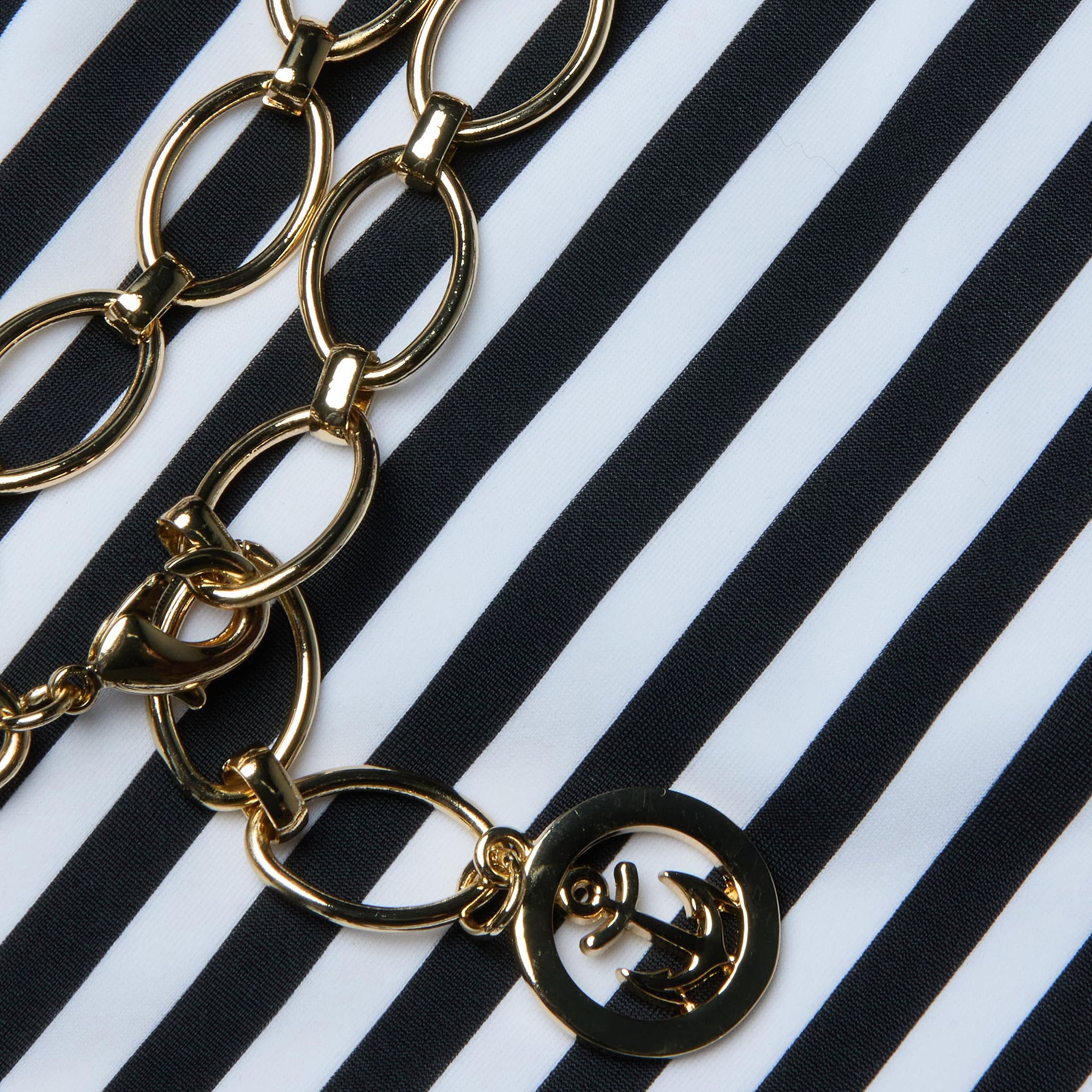 The Nicole Bikini Bottom by L'AGENCE is displayed on black and white stripes, embodying Parisian glamour.
