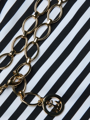 The Nicole Bikini Bottom by L'AGENCE is displayed on black and white stripes, embodying Parisian glamour.