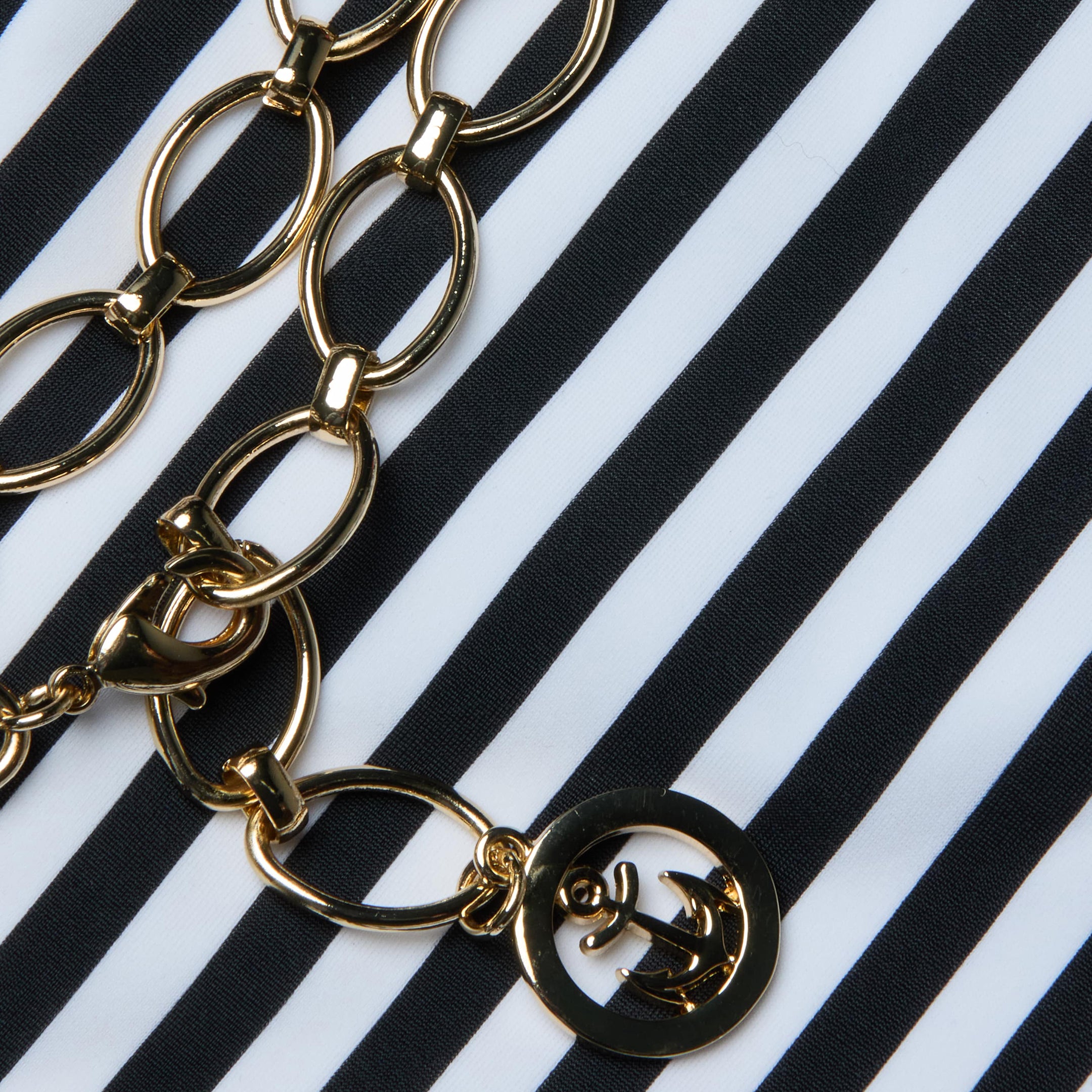 The Nicole Bikini Bottom by L'AGENCE is displayed on black and white stripes, embodying Parisian glamour.