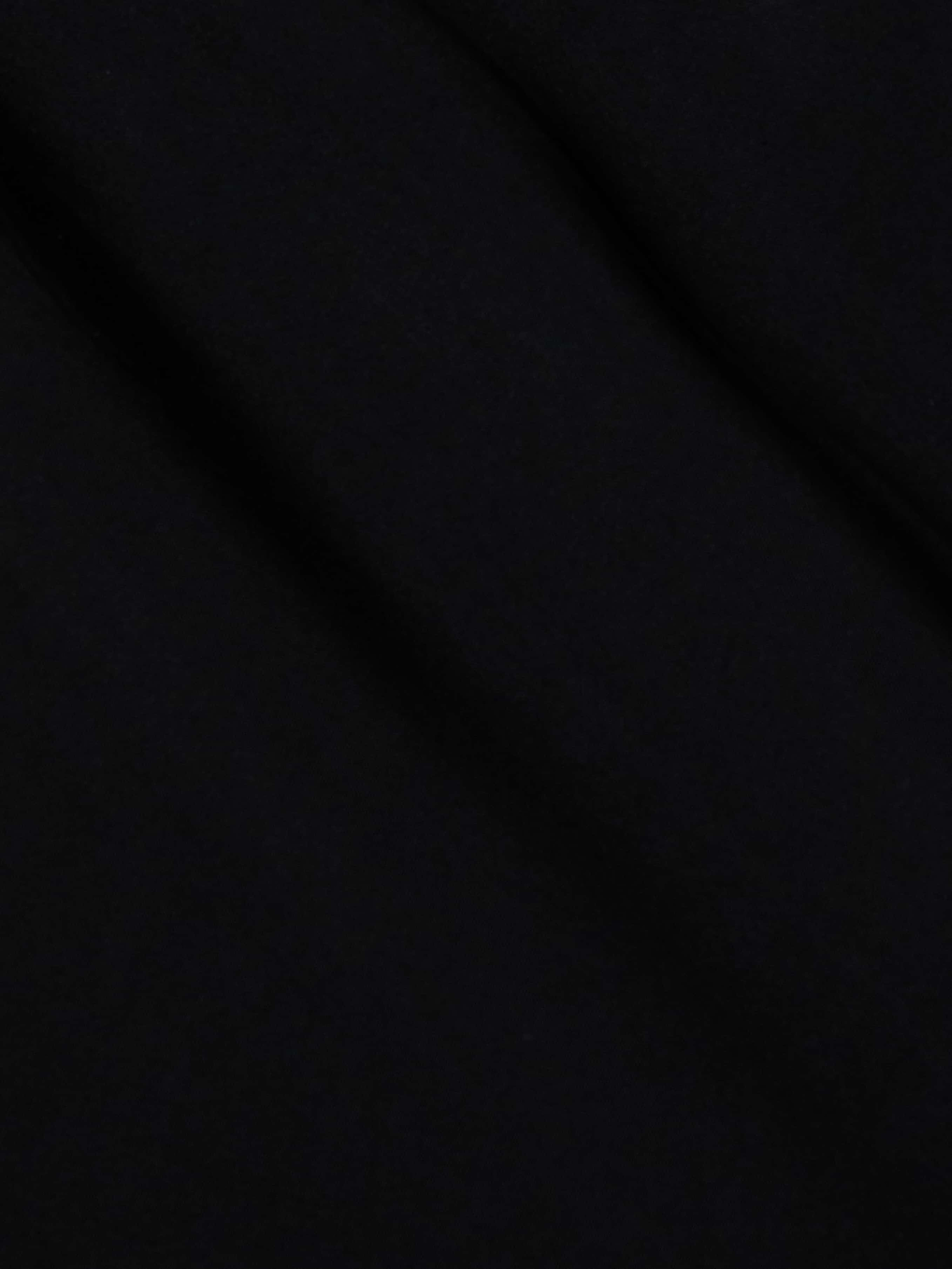 The Klaire Cover-Up Skirt features solid black viscose chiffon with subtle diagonal folds and a soft texture, creating gentle shadows across its surface.