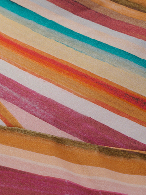 A close-up of the Remi One-Piece Swimsuit shows diagonal watercolor stripes in pink, orange, yellow, green, and white, forming a vibrant abstract pattern.