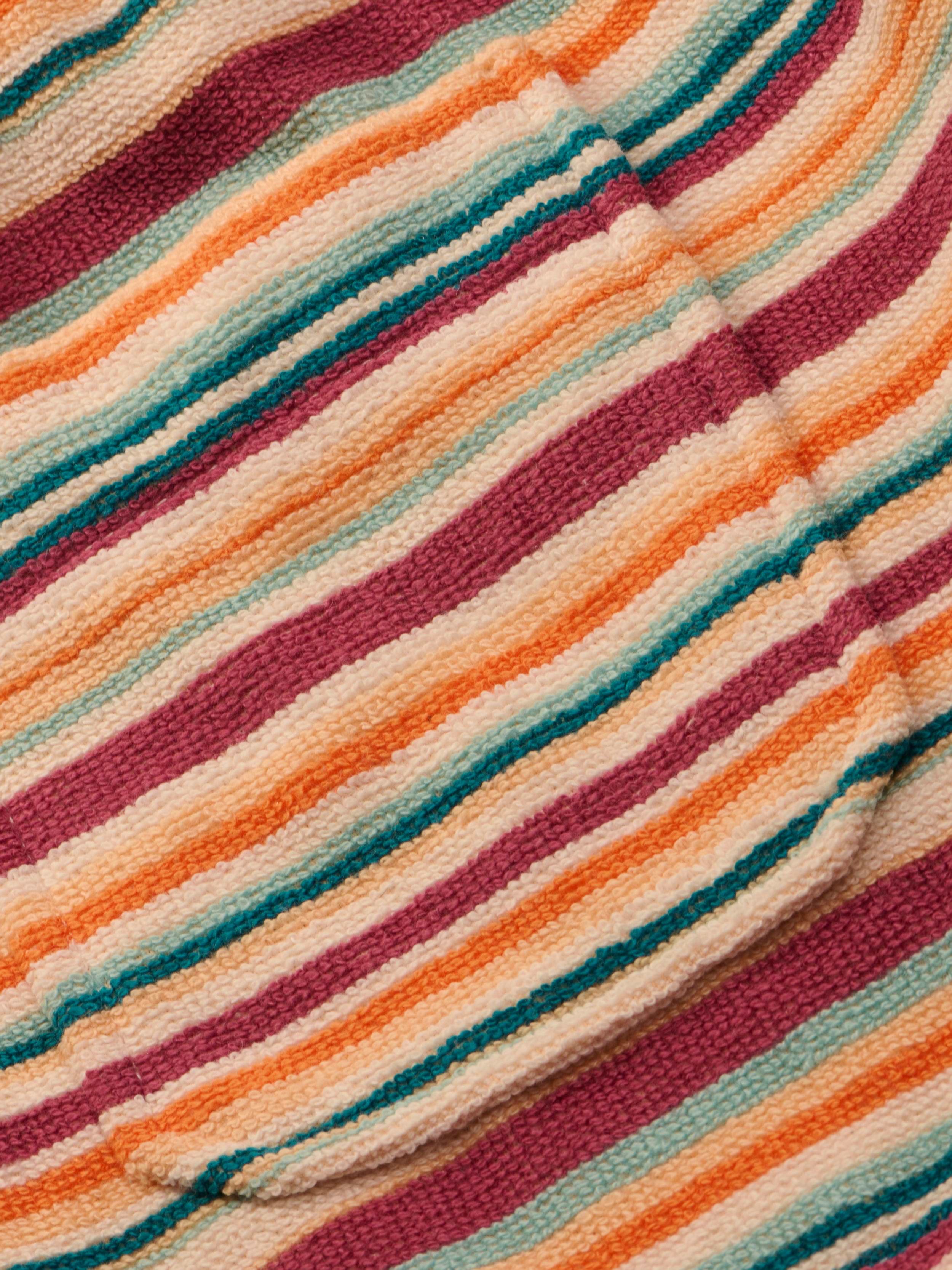 Close-up of the Amiya Cover-Up Short, showcasing its textured fabric with horizontal stripes in shades of orange, pink, cream, and teal. The soft, subtly ribbed material evokes the comfort of cozy terrycloth—perfect for poolside lounging.
