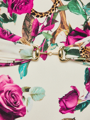 Close-up of the Lisa Plunge One-Piece Swimsuit, featuring UPF 50 fabric with a vibrant rose leopard print, pink roses, green leaves, and two pieces joined by a gold metal clasp in the center.