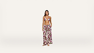 Woman standing barefoot against a plain background, wearing a floral bikini top and matching wide-leg pants with pockets. She has long hair and a relaxed expression, with one hand in her pocket.
