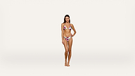 A woman stands barefoot on a plain white background, wearing a colorful floral bikini. She has long hair and is posing with one hand on her hip, looking directly at the camera.