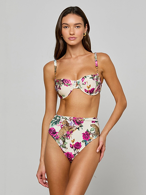 A woman poses against a light gray background, wearing the Alexandria Bikini Top—a high-waisted balconette style in pink, green, and beige rose leopard print. UPF 50 fabric provides extra sun protection.