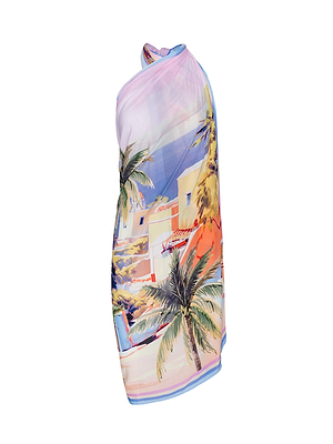 The Maribel Cover-Up Pareo is a vibrant one-shoulder dress with a postcard print of palm trees and pastel buildings, elegantly draped on a white background.