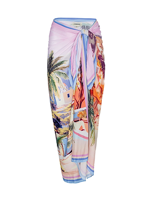The Maribel Cover-Up Pareo is a long skirt with a vibrant print of palm trees, houses, and a coastal scene, featuring a knotted front waist detail.