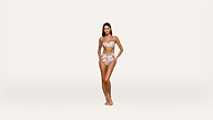 A woman stands barefoot against a plain white background, wearing a floral strapless bikini top and high-waisted bikini bottoms, with one hand resting on her hip.