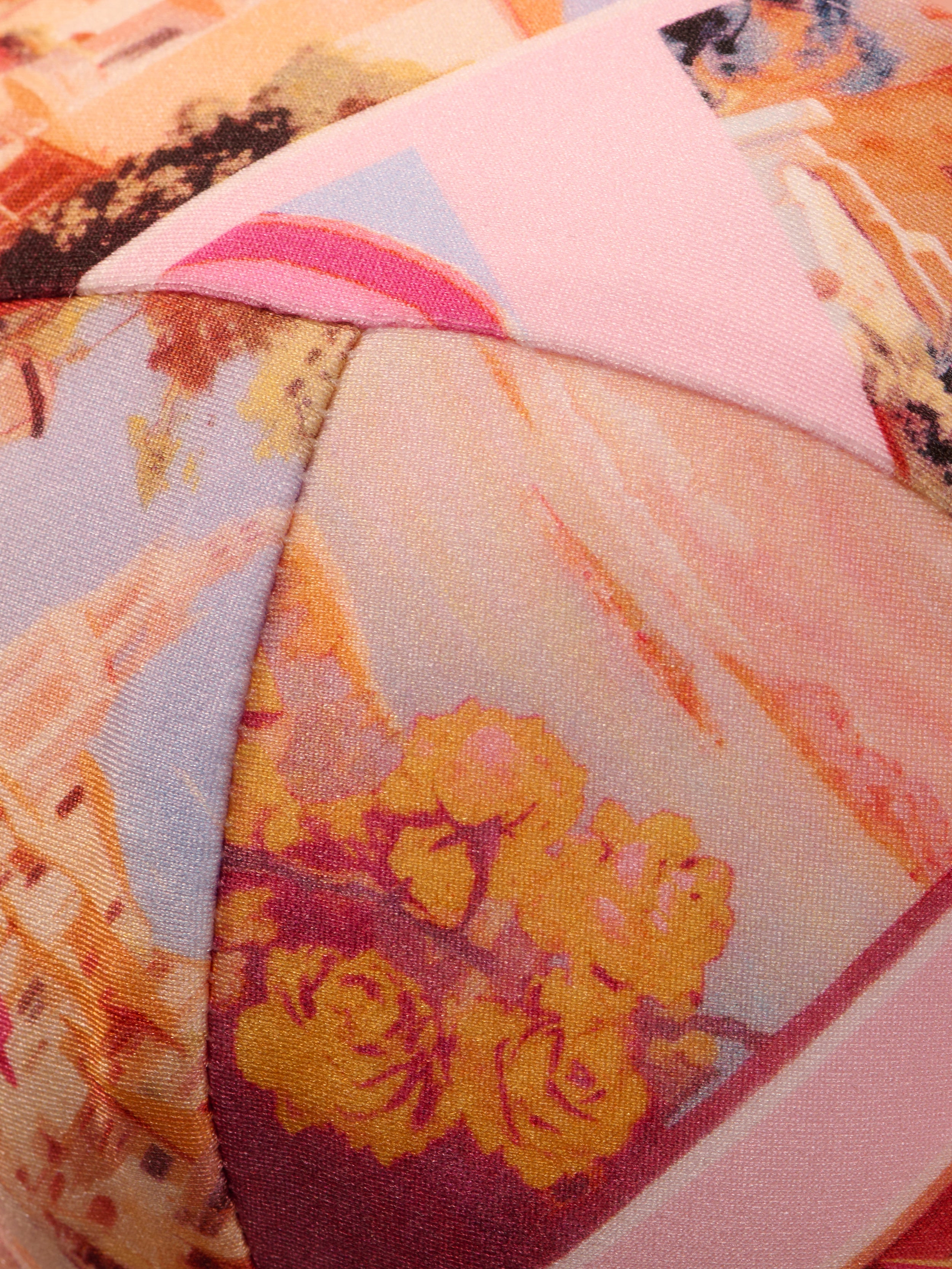 Close-up of the Alexandria Bikini Top, featuring colorful, patterned fabric with abstract shapes and floral prints in shades of pink, yellow, and orange—reminiscent of a vibrant postcard print—and detailed stitched seams.
