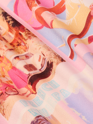 Close-up of patterned fabric with colorful, retro-style illustrations of women wearing the Violet String Bikini Bottom and hats, postcard print details, and partially visible FRENCH RIVIERA text on a soft pink background.