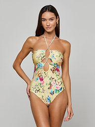A woman models the Shiva One-Piece Swimsuit, featuring a yellow butterfly print and front keyhole cutouts, against a plain light gray background.
