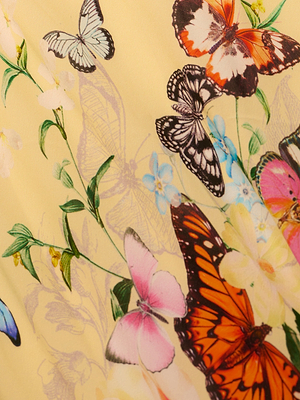 Illustration of colorful butterflies fluttering among green leaves and white and yellow flowers on a pale yellow background—reminiscent of the Klaire Cover-Up Skirt in airy viscose chiffon.