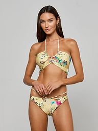 A woman with long brown hair poses against a plain background wearing the Sirena Bikini Top, a yellow butterfly print halter bikini paired with matching bottoms. She looks at the camera with a neutral expression.