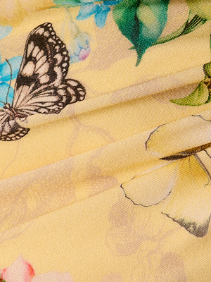Close-up of the Sirena Bikini Top in yellow, featuring a butterfly and floral print with detailed black and white wings, vivid flowers, green leaves, and hints of pearl accents for elegant texture on the softly folded fabric.