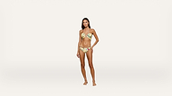 A woman stands barefoot against a plain white background, wearing a light-colored, floral-patterned bikini. She has long, dark hair and her left hand rests on her hip.