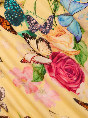 A close-up of colorful butterflies and vibrant flowers, including roses, printed on pleated yellow fabric—perfect for the Jean Bikini Bottom with a high-leg, low-rise cut.
