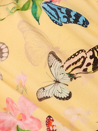 Close-up of the Nicole Bikini Bottom’s yellow fabric, showcasing a delicate and vibrant pattern with multicolored butterfly prints—featuring blue and white—and pink flowers.