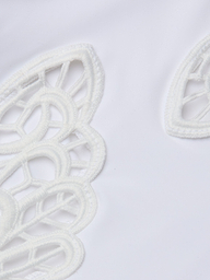 Gros plan sur le tissu blanc du maillot de bain une pièce Remi, qui présente des découpes brodées décoratives aux formes incurvées semblables à des pétales et des applications de papillons pour un look délicat inspiré de la dentelle.