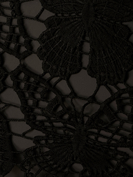 Close-up of the Janus Cover-Up Robe in black lace fabric, showcasing an intricate butterfly crochet pattern with delicate threads forming detailed wings and a finely textured appearance.