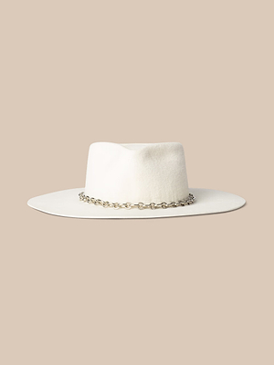 The Umbra Hat, made in LA from white felt velour, features a silver chain band on the crown and is shown on a beige background.