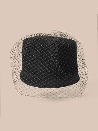 The Rawle Mini Cap is a black handcrafted hat adorned with a delicate, diamond-patterned black veil, set against a beige background.