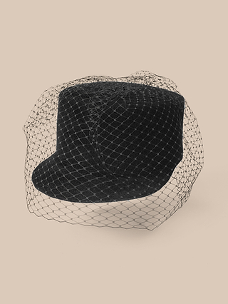 The Rawle Mini Cap, a black baseball cap adorned with delicate black mesh netting reminiscent of a chic veiled mini cap, is displayed against a plain beige background.