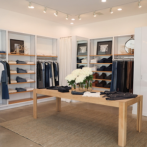 Clothing store interior with racks, a table, and decorative elements.