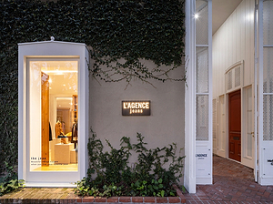 Modern building entrance with 'L'AGENCE' sign and illuminated interior.