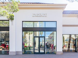 Storefront of L'AGENCE with glass doors and windows.