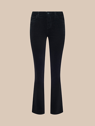 A pair of Petite Stevie Velvet Jeans in black, featuring a flared silhouette with a high rise and front and back pockets, shown against a plain beige background.