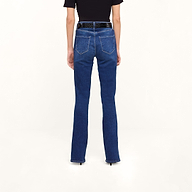 A person stands facing away, wearing Petite Selma Bootcut Jeans in dark blue super stretch denim with a black belt and a short-sleeve black top, against a light background.